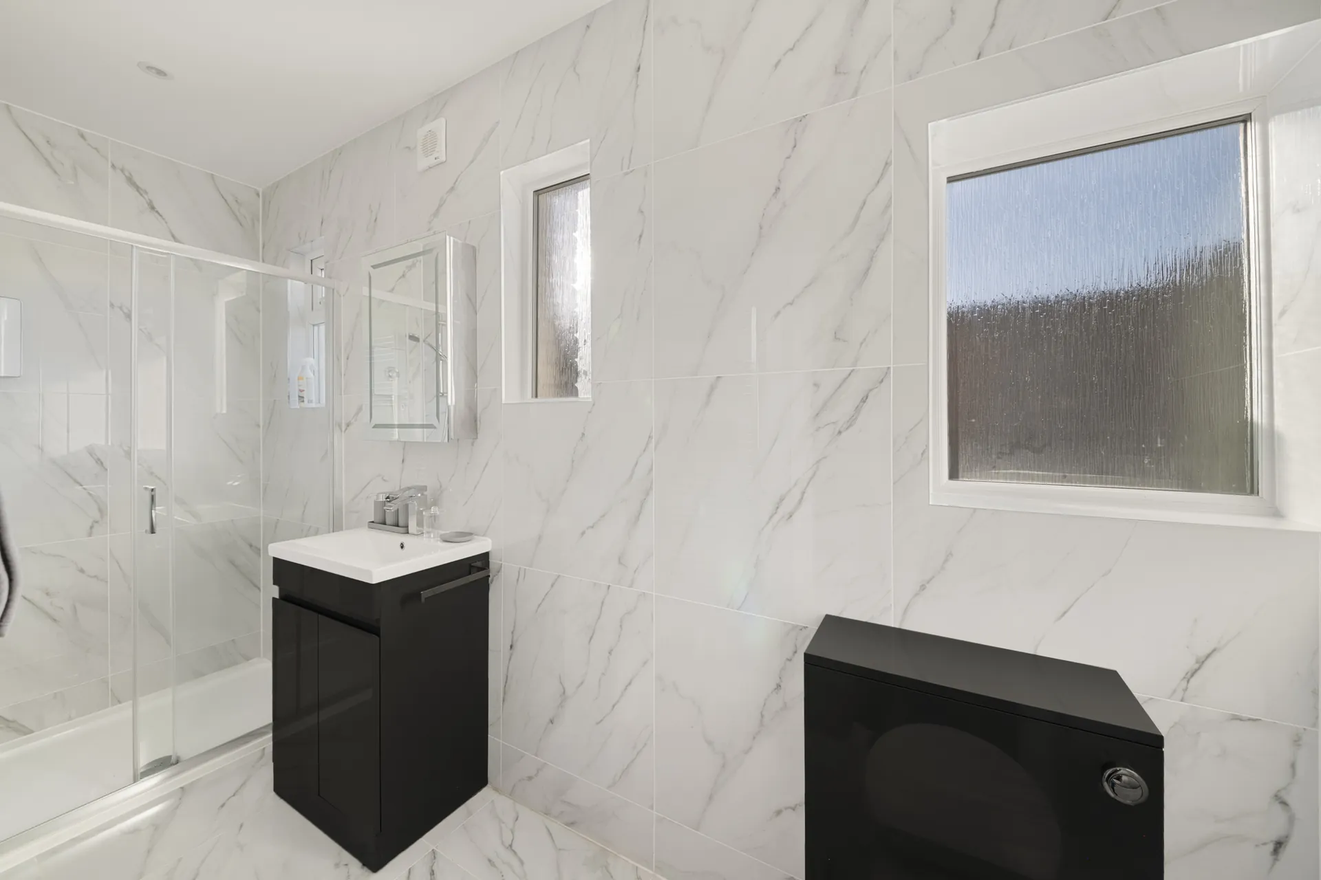 The bathroom, tiled floor to ceiling in marble-effect porcelain