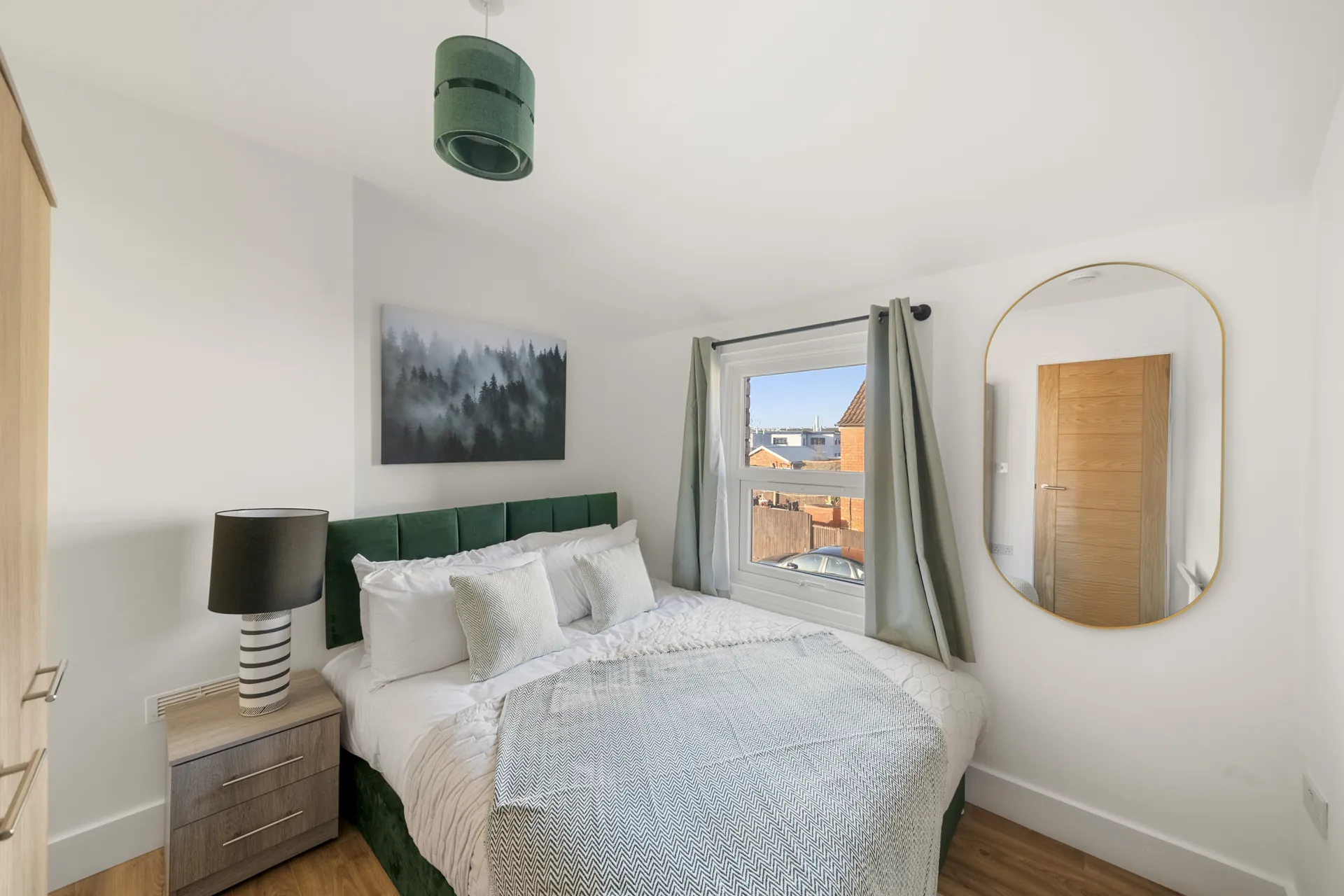 Velvet headboard, round mirror and bedside lamps