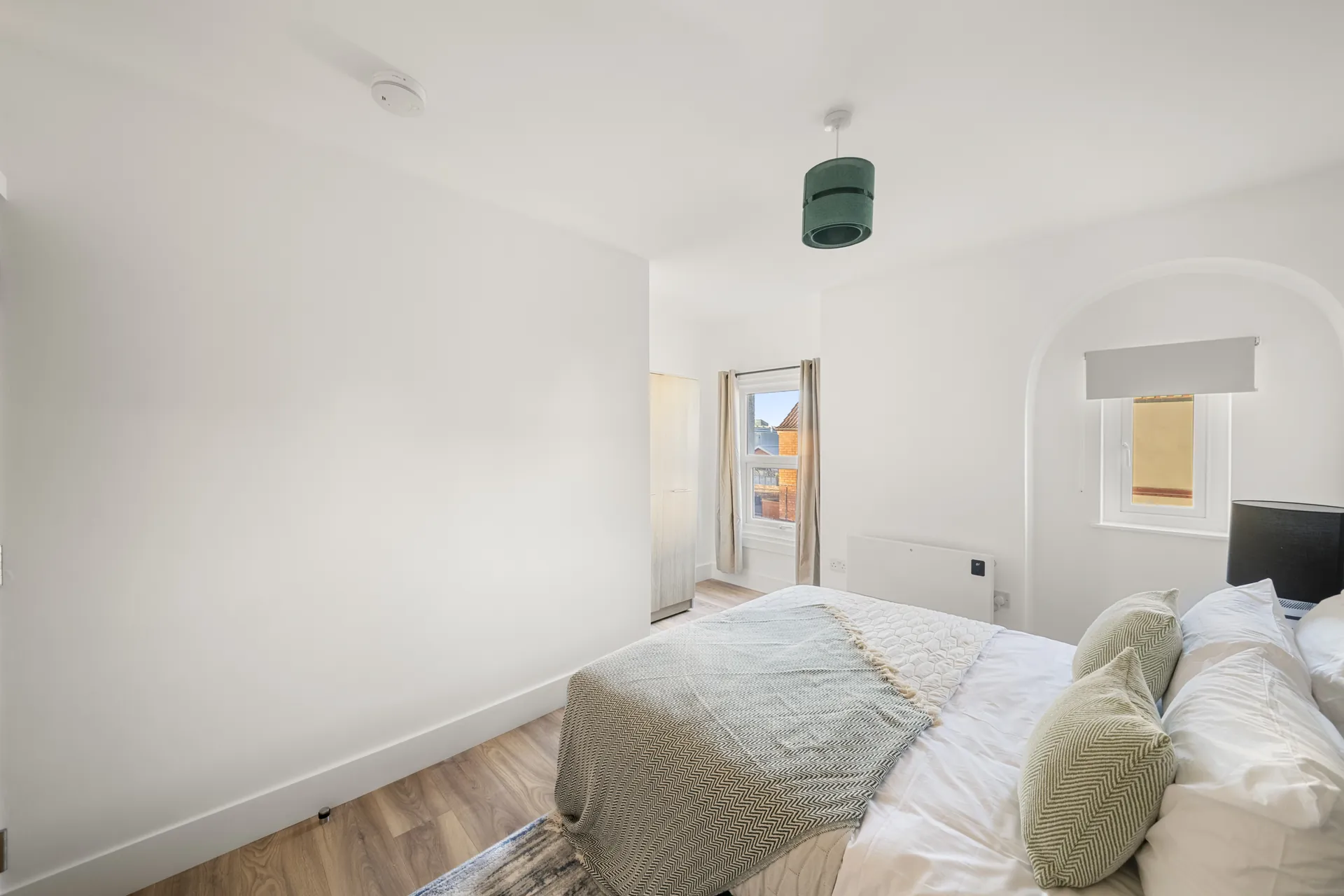 Soft sage bedding over warm oak flooring